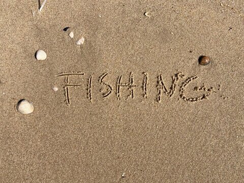 on the beach is carved with letters in the smooth sand the writing Fishing