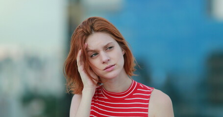 Tired young redhead woman feeling headache outside thinking deeply