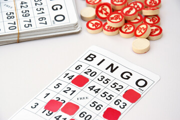 Many wooden chips with numbers and cards for a board game of bingo or lotto on a light background.
