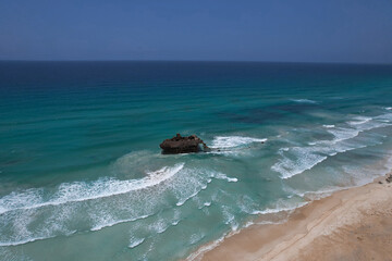 Fototapeta na wymiar Sunken ship in the ocean near the sandy beach, drone view