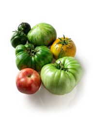 Whole and halved fresh green unripe and ripe yellow and red tomatoes isolated on white background. Organic, fresh food produce.