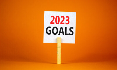 2023 Goals symbol. White paper with words 2023 Goals, clip on wooden clothespin. Beautiful orange table orange background. Business and 2023 goals concept. Copy space.