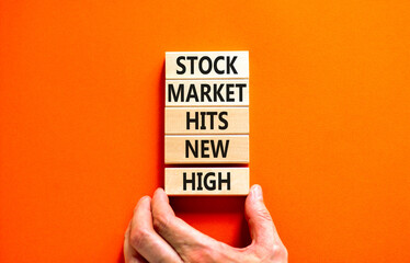 Stock market hits new high symbol. Concept words Stock market hits new high on wooden blocks on a beautiful orange background. Businessman hand. Business stock market hits new high concept. Copy space