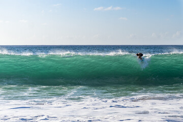 Silhouette of a surfer riding a wave in Waimea Beach, North shore of Oahu, Hawaii