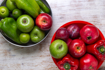 Fototapeta na wymiar Madrid, Spain October 6, 2020 Green and red fruits and vegetables inside containers of the same color on weathered white wooden table