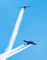 Silhouettes of training aircraft performing aerobatics on a clear sunny day. - obrazy, fototapety, plakaty