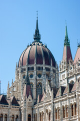Obraz premium The red roof dome of the Parliament House in Budapest, Hungary, is only a small part of the massive government buildings with awesome spires, arches, towers, and railings.
