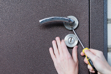 Handyman installing door lock in door with screwdriver. Checking lock for operability in door closeup.