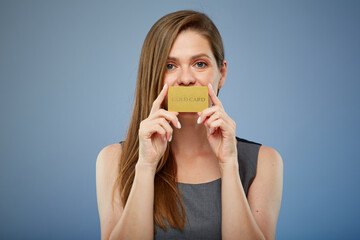 Smiling woman holding gold credit card in front of mouth. isolated portrait.