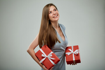 Happy business woman in dress holding two red gifts isolated on gray. Girl looking away.