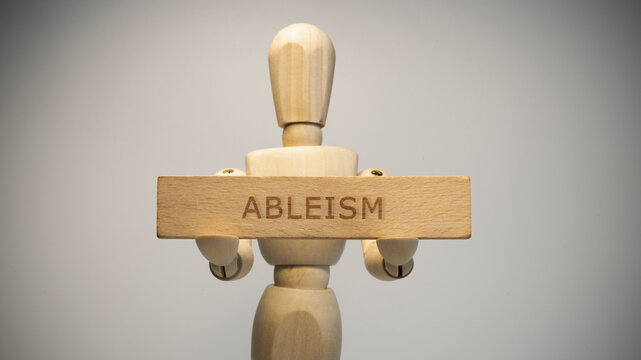 Ableism written on wooden surface. Close-up in the studio.