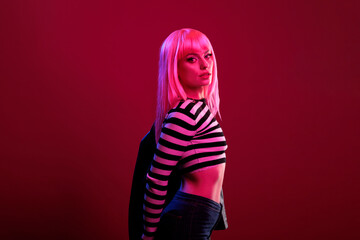 Young caucasian woman feeling sexy in fluorescent pink light, dark colorful lighting to create trendy pictures. Female model posing with confidence and natural emotions, beautiful style.