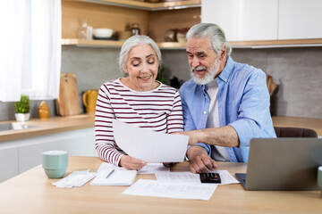 Financial Planning On Retirement. Senior Couple With Laptop And Papers In Kitchen