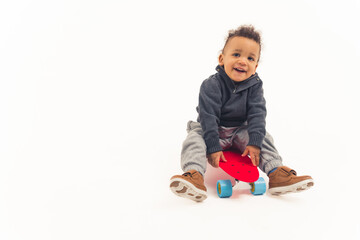 cute little boy sitting on the skateboard, studio shot isolated copy space full shot. High quality photo