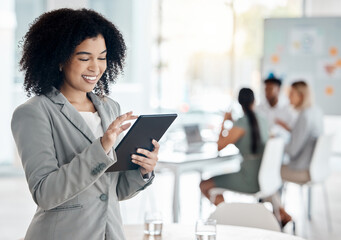 Business woman working on a digital tablet doing research while in a team meeting in the office. Corporate employee reading information on the company website with technology in a conference room.