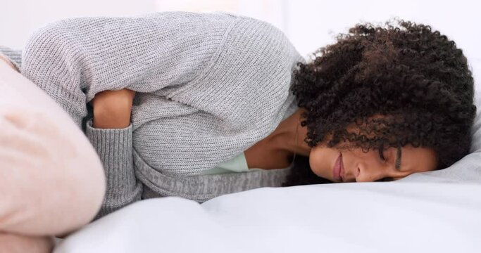 Bed, stomach pain and young woman doing massage on tummy for menstruation ache relief problem. Sad, sick and frustrated girl feeling stress from abdomen cramps while lying down in bedroom.