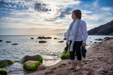 Boy walking on the beach in nice clothes.