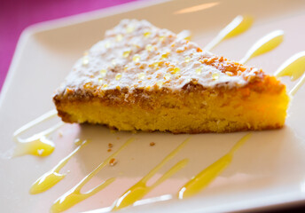 Delicious almond pie Tarta de Santiago served with orange sauce on white plate