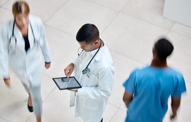 Tablet, healthcare and medicine with a man doctor working in a busy hospital with urgency. Medical,...