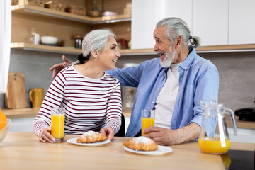 Fototapeta na wymiar Portrait Of Happy Senior Spouses Having Snacks In Kitchen Together