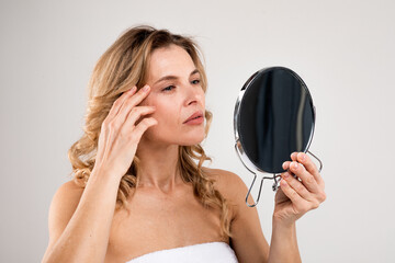 Skin Aging. Attractive Middle Aged Woman Holding Mirror And Looking At Wrinkles