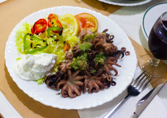 Fried octopus dish with vegetables and wine. High quality photo