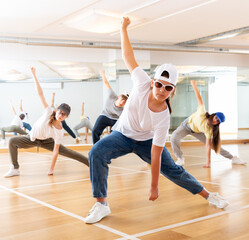 Fototapeta na wymiar Group of teenagers in casual clothes training hip-hop in class, learning modern dance movements
