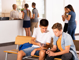 School Boys using phones, have rest between lessons at hallway in school