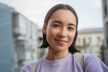 Smiling asian tourist taking selfie outdoors. Beautiful Korean woman wearing purple casual t shirt...