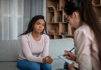 Personal mental consultation. Unhappy sad millennial black lady looking at european doctor woman in...