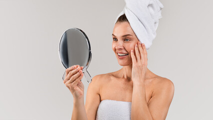 Skincare Treatments. Middle aged lady with towel on head looking in mirror