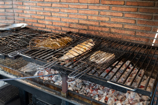 Fresh fish grilling on old charcoal parrillas build outside of buildings in small fisherman's village Getaria, Basque Country, Spain