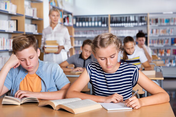 Fototapeta na wymiar Schoolgirl writing lesson in classroom, teacher on the background
