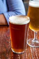 Pint glasses of british ale and lager beer served in old vintage English pub