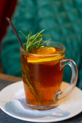 Cup of winter hot tea with fresh citrus fruits and rosemary