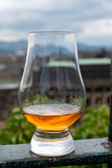 Glass of single malt scotch whisky and view from Calton hill to park and old parts of Edinburgh city in rainy day, Scotland, UK