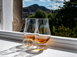 Two glasses of single malt scotch whisky served on old window sill in Scottisch house with view on old part of Edinburgh, Scotland, UK