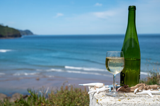 Txakoli or chacol&iacute; slightly sparkling very dry white wine produced in the Spanish Basque Country, served outdoor with view on Bay of Biscay, Atlantic Ocean.