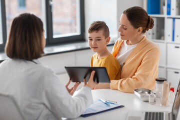 medicine, healthcare and pediatry concept - smiling mother with little son and doctor with tablet pc computer at clinic