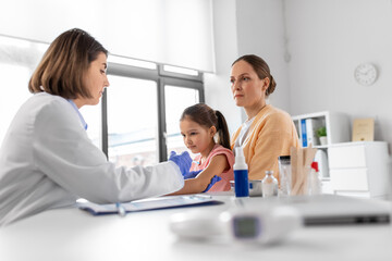 Fototapeta premium medicine, healthcare and pediatry concept - female doctor or pediatrician with syringe making vaccine injection to little girl patient at clinic
