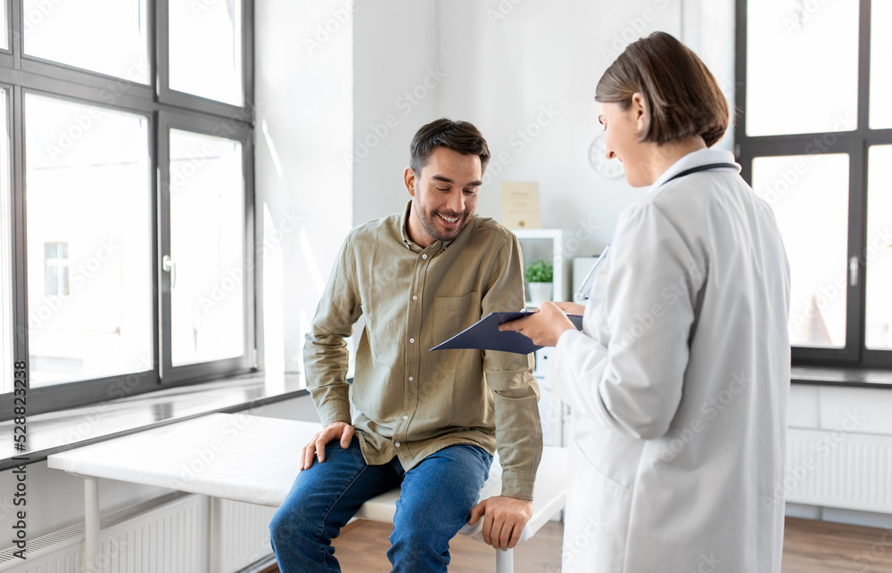 Wall mural medicine, healthcare and people concept - female doctor with clipboard and happy smiling man patient meeting at hospital