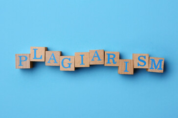 Word Plagiarism made of wooden cubes with letters on light blue background, top view
