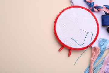 Flat lay composition with embroidery hoop on beige background. Space for text
