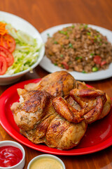 Grilled chicken with french fries on a wooden table.

