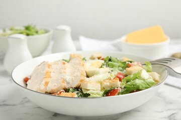 Delicious Caesar salad in bowl on white marble table