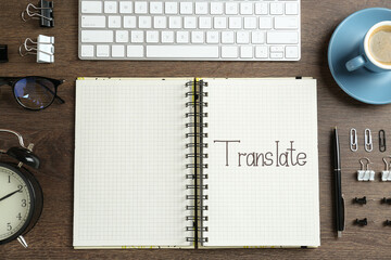 Flat lay composition with word Translate written in notebook and stationery on wooden table