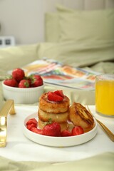 Tasty breakfast served in bedroom. Cottage cheese pancakes with strawberries and honey on white tray