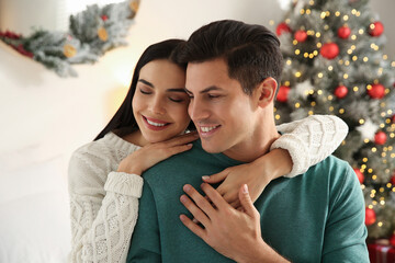 Fototapeta premium Happy couple near decorated Christmas tree indoors