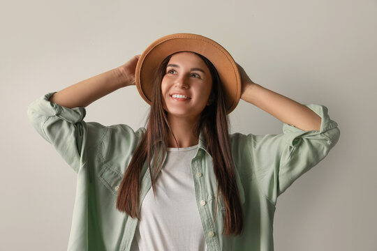Smiling young woman in stylish outfit on light background