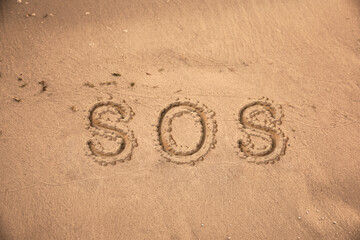 SOS message drawn on sandy beach, top view